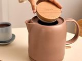 a person pouring coffee into a teapot on a table