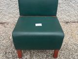 une chaise verte posée sur le trottoir, près d'un mur