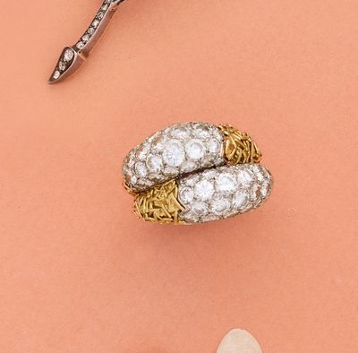 une paire de ciseaux et une bague posés sur une surface rose