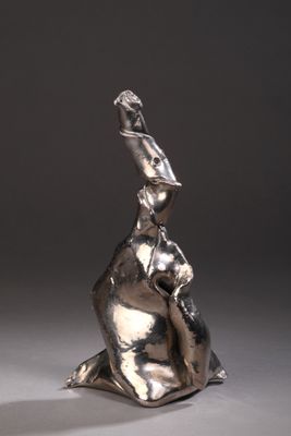 sculpture en argent représentant une femme assise sur un rocher, les mains levées