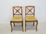 two wooden chairs with yellow upholstered seats against a white wall