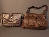 pair of brown leather handbags with tassels on a grey background
