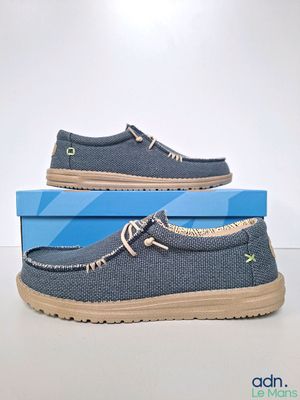 men ' s blue canvas boat shoes with tan soles on top of a blue box