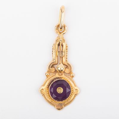 a close up of a gold pendant with a purple stone