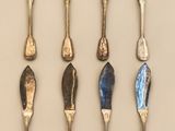 several spoons and forks are lined up on a white surface