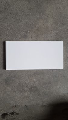 an overhead view of a white rectangular tile on a concrete floor