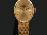 une photo d'une montre-bracelet dorée posée sur une surface noire