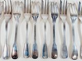 a lot of forks and spoons on a white table