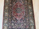 un tapis persan ancien posé sur un parquet dans une pièce