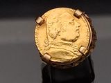 l'image d'une bague en or sur laquelle se trouve une pièce de monnaie