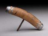 un objet en bois muni d'une poignée métallique, posé sur une surface grise