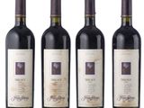 three bottles of red wine are lined up on a white surface