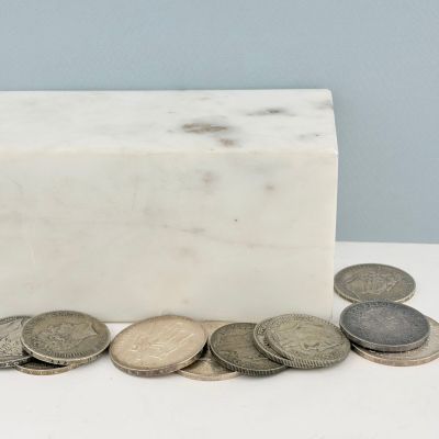 un bloc de marbre blanc avec des pièces de monnaie posé sur une table