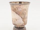 une coupe en argent ancien posée sur un socle, sur fond blanc