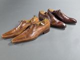 two pairs of brown shoes sitting on top of a table