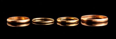 three gold wedding rings sitting in a row on a black surface