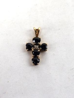 a gold cross pendant with black stones on a white background