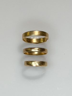 three gold rings sitting on top of each other on a white surface