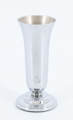 un vase en argent posé sur un plateau en argent, sur fond blanc