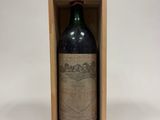 une vieille bouteille de vin dans une caisse en bois posée sur une surface blanche