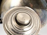 a silver vase sitting on a table with a chain around it
