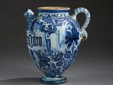 a blue and white vase with a handle on a gray surface