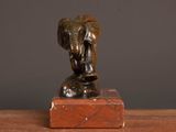statue of an elephant on a marble block on a wooden table