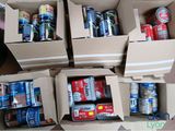 several boxes of cans of soda and cans of soda sitting on a table