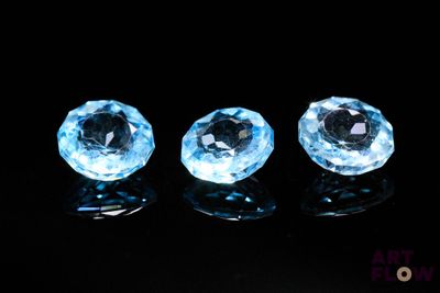 trois pierres précieuses de topaze bleue posées sur une surface noire