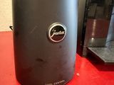 the coffee machine is sitting on the red table next to the coffee maker