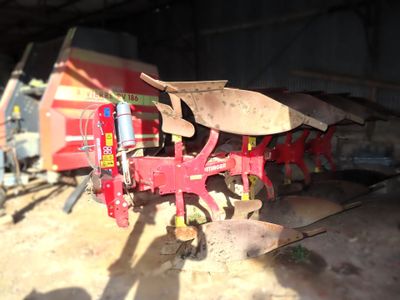 a red tractor with a plow attached to it ' s back