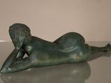 statue of a woman laying on her back on a glass table