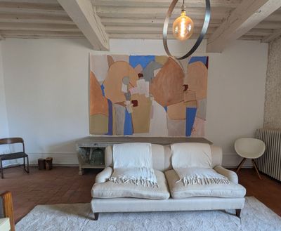 a white couch in a living room with a painting on the wall behind it