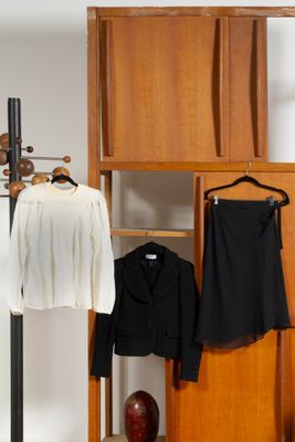 un porte-manteau sur lequel sont accrochées deux vestes et une jupe