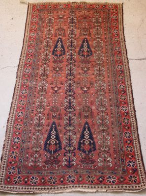 un tapis persan ancien présentant un motif géométrique sur fond rouge