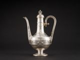 une cafetière ancienne en argent avec une anse, sur fond noir
