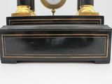 a black and gold clock on a stand on a white background