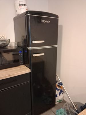 a black refrigerator in the corner of a kitchen
