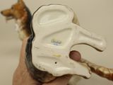 a hand holding a dog figurine with a bone in it ' s mouth