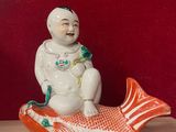 une figurine représentant un homme assis sur un poisson