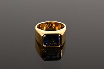 a close up of a gold ring with a blue stone