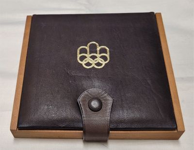 un livre en cuir marron ouvert, orné d'un symbole olympique doré