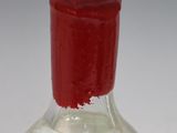 a glass bottle with a red lid on a white table