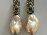 deux paires de boucles d'oreilles en perles et diamants exposées dans une vitrine
