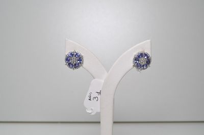 une paire de boucles d'oreilles en cristal bleu et blanc, posées sur un socle blanc