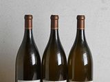 trois bouteilles de vin sont alignées sur une table en bois