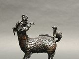 bronze statue of a goat with a bird on its back