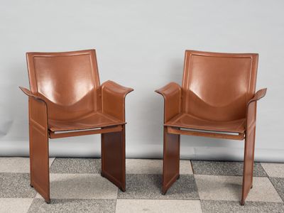 deux fauteuils en cuir marron placés l'un à côté de l'autre sur un sol à carreaux