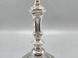 a close up of a silver candle holder on a white surface