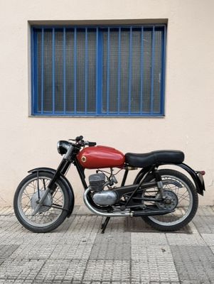 a red motorcycle parked in front of a building with a blue window